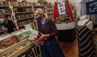 Masks Off - Art A photo of a woman working in a small retail store wearing a mask.